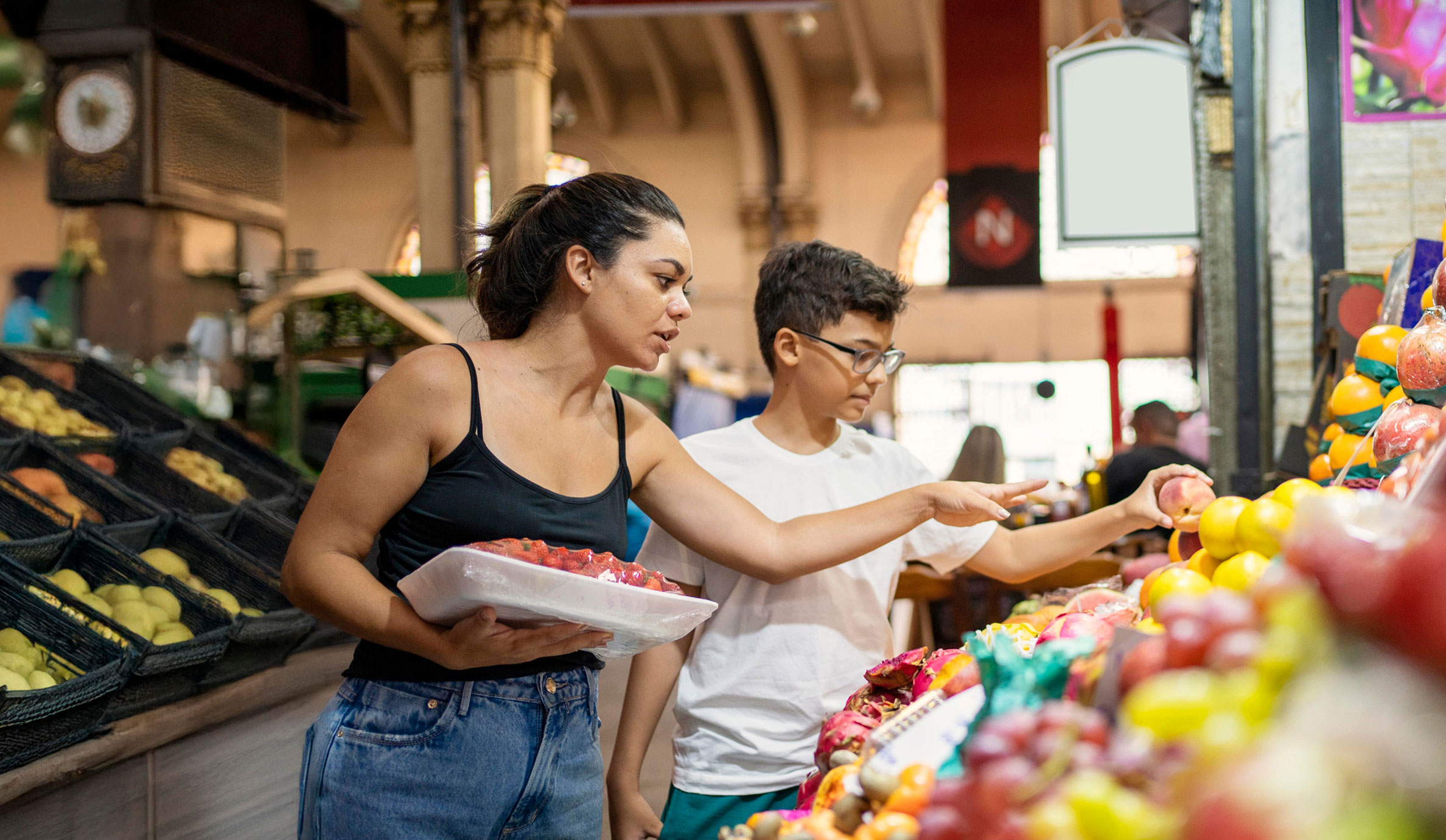 Mother shopping for fresh fruit with her son